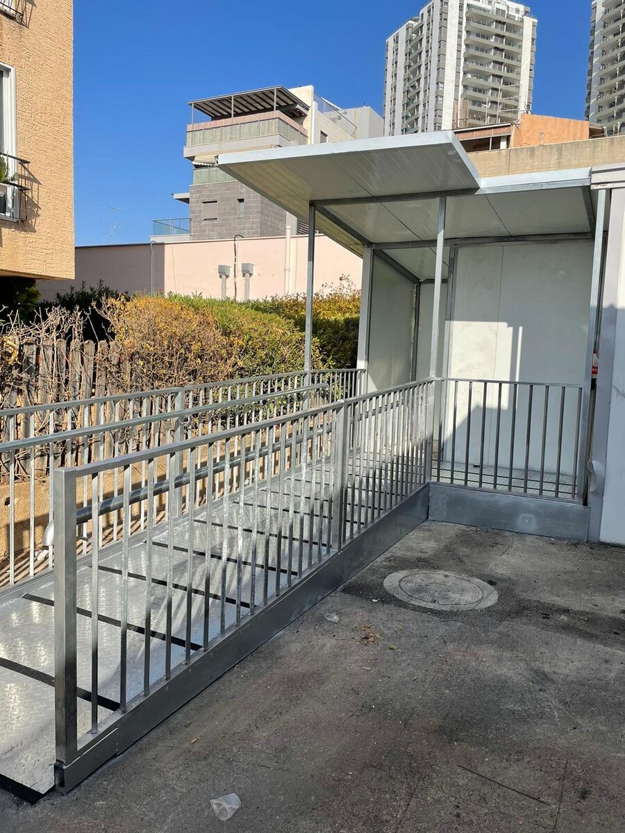 רמפת פלדה מגולוונת עם מעקות וקירוי בכניסה למבנה