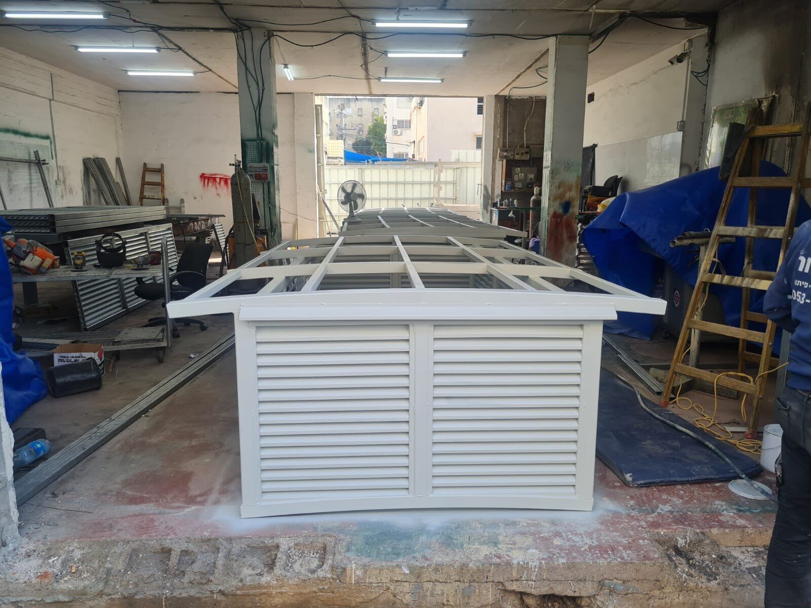 מבנה מתכת לבן עם תריסי אוורור וקונסטרוקציית גג